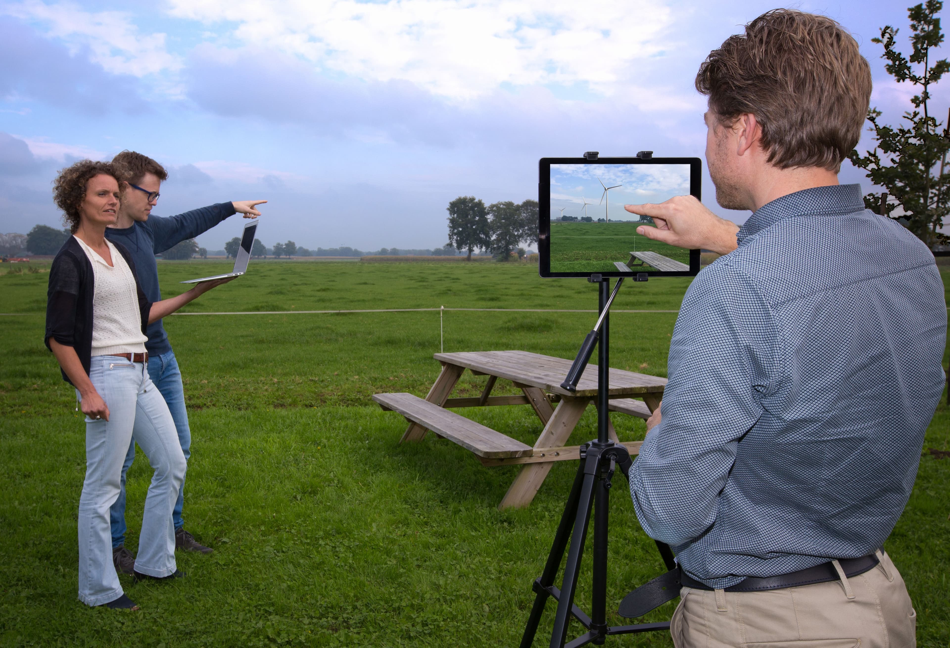 2 mensen in een veld wijzen naar een windturbine
