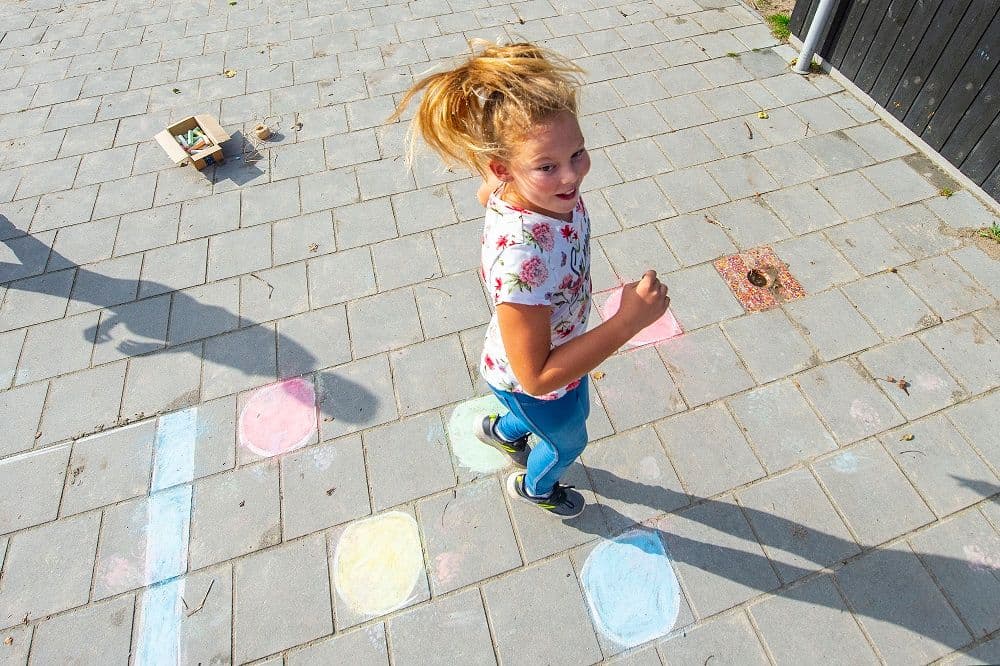 Meisje op stoep met stoepkrijt