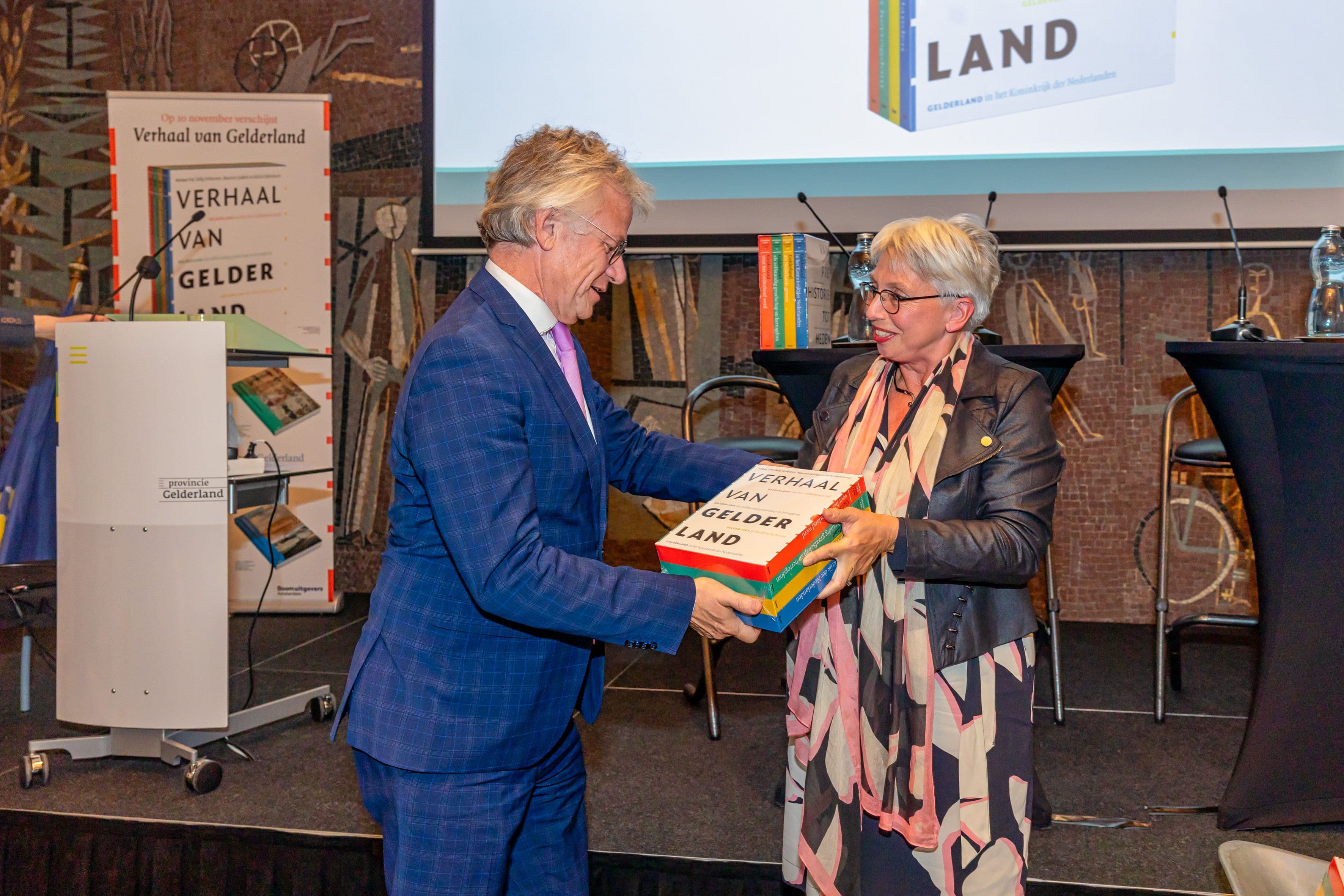 John Berends krijgt de vier boeken overhandigt door Dolly Verhoeven